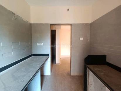 Room under renovation with unfinished walls, black baseboard countertop, and doorway leading to an adjacent interior space. in Rustomjee Athena